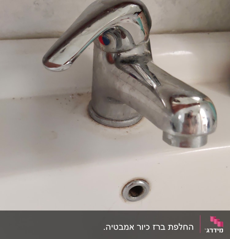ברז כרום על כיור לבן עם כתמי לכלוך
